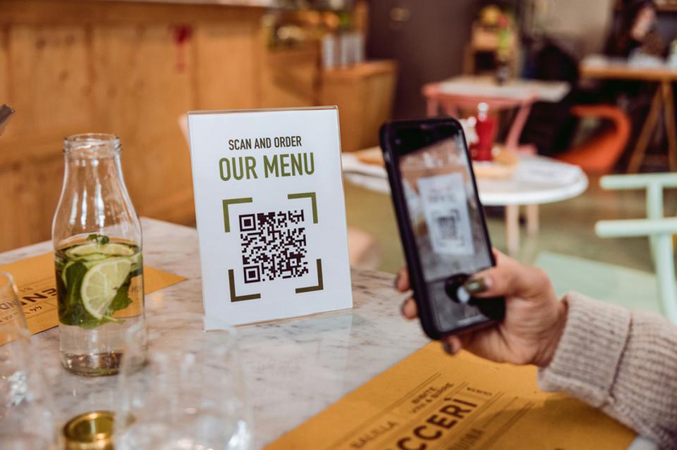 Customer uses QR code on sign that reads "Scan and Order: Our Menu"